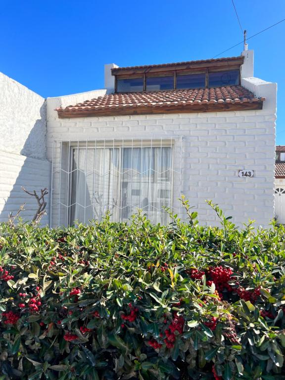 a house with a hedge of redberries in front of a building at Casa MAR in Playa Unión