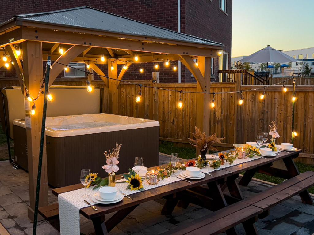 una mesa en un patio trasero con bañera de hidromasaje y luces en Elevate Your Family Getaway in Oshawa with the brand new Luxury Villa, en Oshawa
