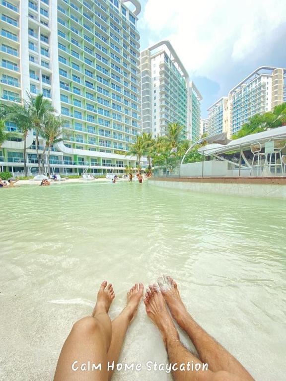 a person laying on the beach with their feet in the water at Condo in Azure Urban Resort Residences-Paranaque City in Manila