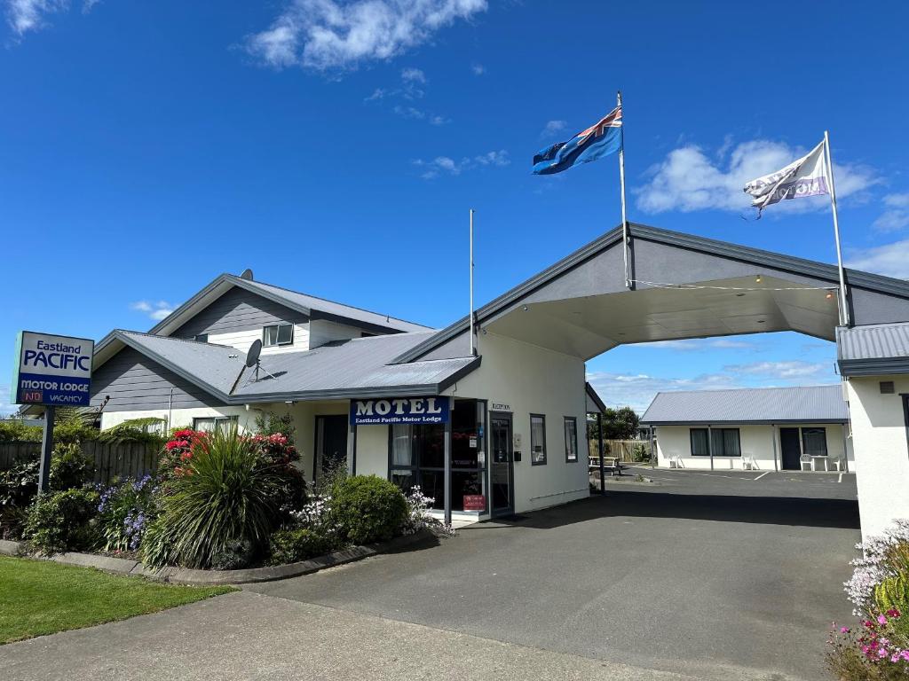 two flags flying in front of a motel at Eastland Pacific Motor Lodge in Opotiki