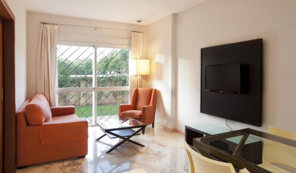 a living room with two chairs and a flat screen tv at Apartamentos Vértice Bib Rambla in Seville