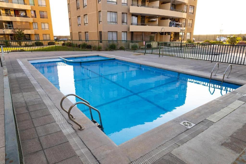 a large blue swimming pool in front of a building at departamento Arica verano 2 habitaciones in Arica