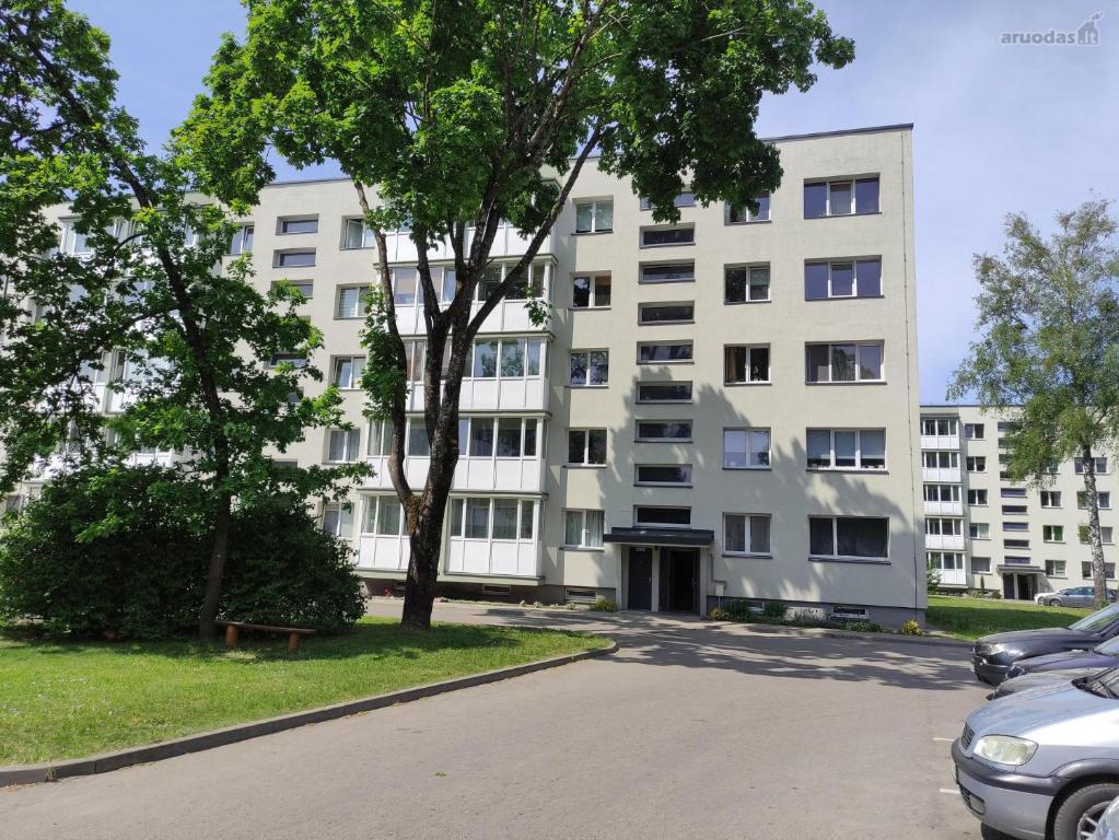 un immeuble d'appartements avec un parking en face de celui-ci dans l'établissement MEŠKUTĖS APARTAMENTAI, à Druskininkai