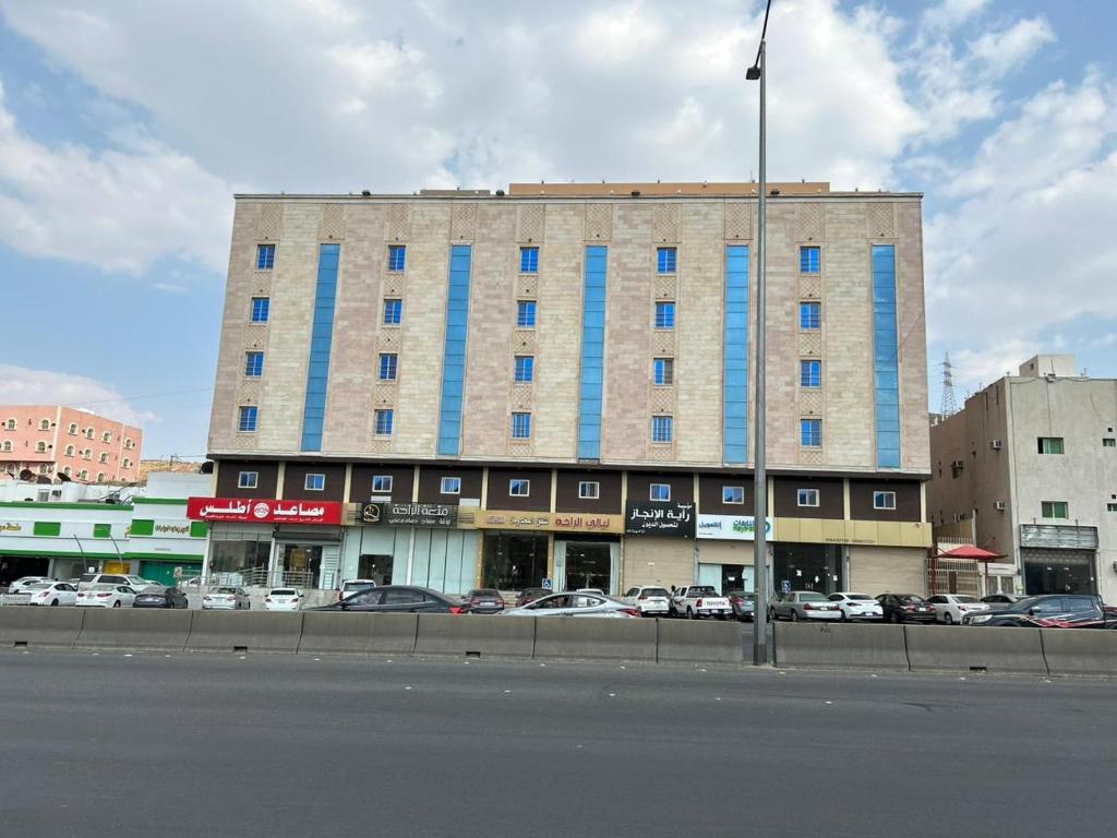un alto edificio con finestre blu su una strada di città di ليالي الراحة للوحدات السكنية a Taif