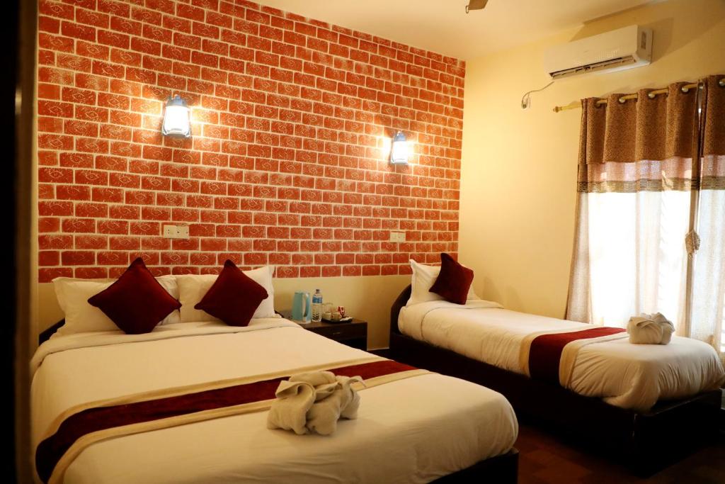 2 Betten in einem Zimmer mit Ziegelwand in der Unterkunft Hotel Vista Chitwan in Sauraha