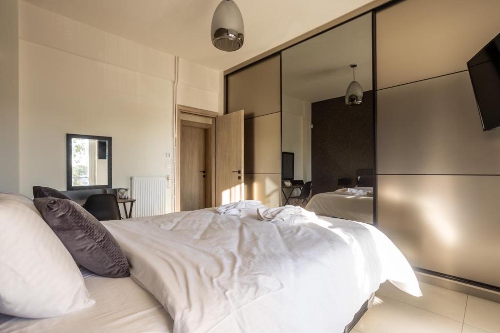 a bedroom with a white bed with a large mirror at AIOLOS GLYFADA luxury sea view suite 5 in Athens