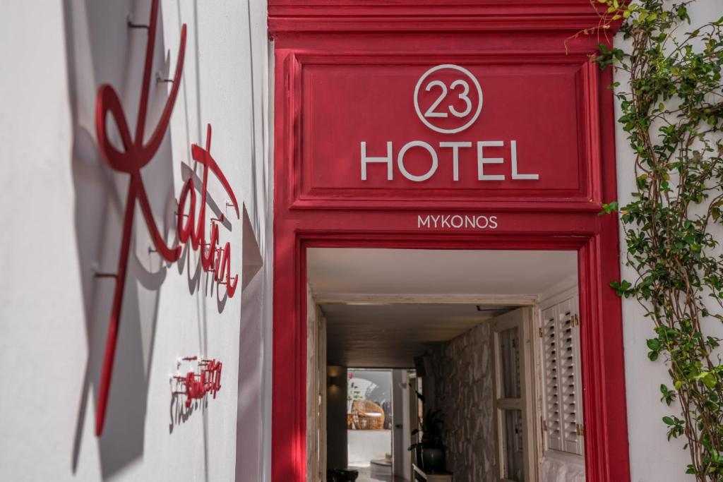 un cartello rosso dell'hotel sul lato di un edificio di 23 Hotel Mykonos a Mykonos Città