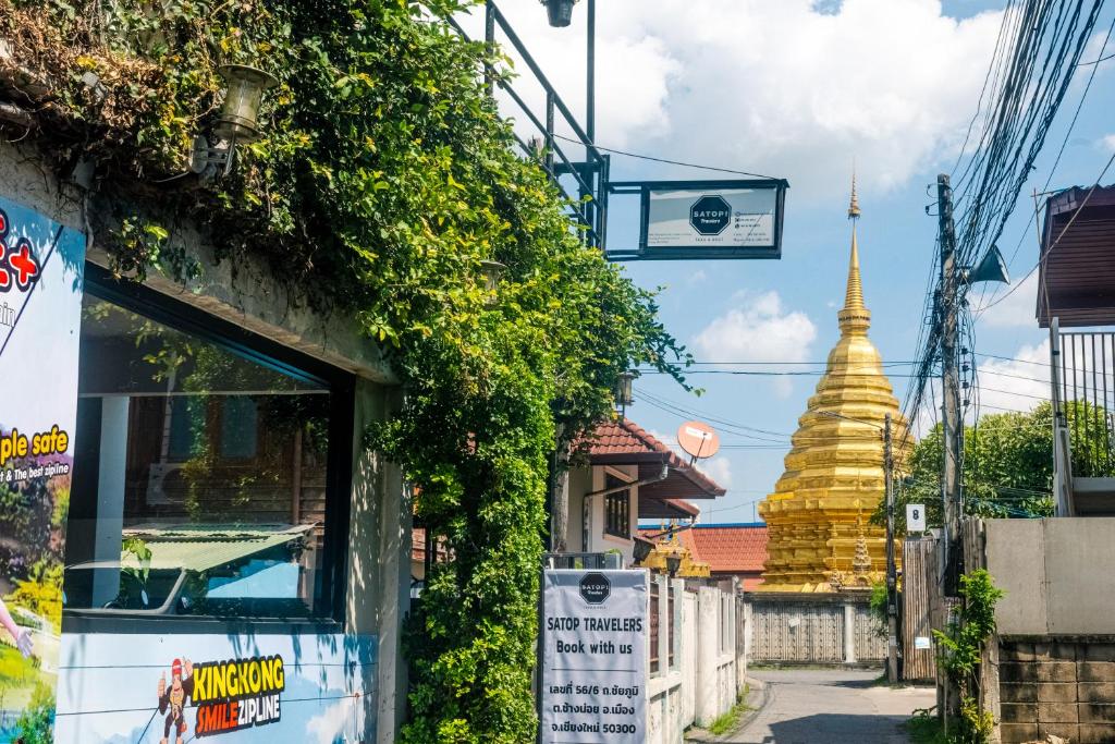a street with a building and a pagoda in the background at Satop travelers Guesthouse in Chiang Mai