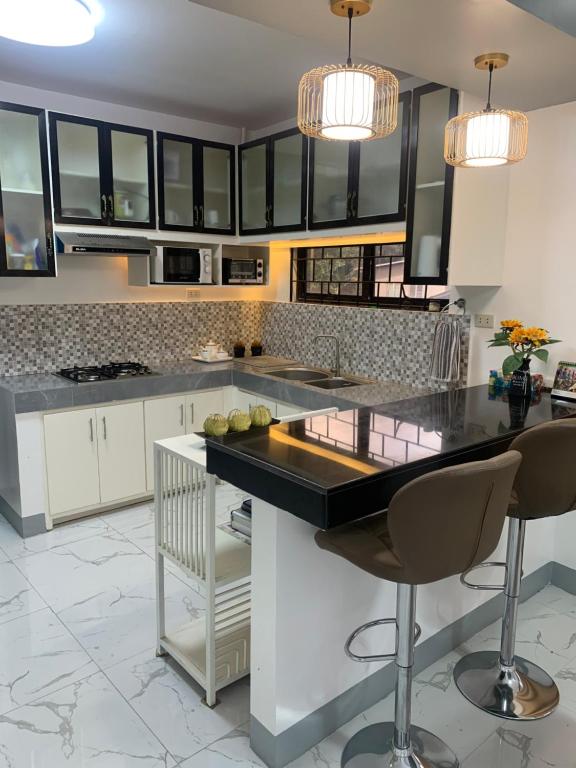 a kitchen with white cabinets and black counter tops at PMPJ Staycation in Lipa