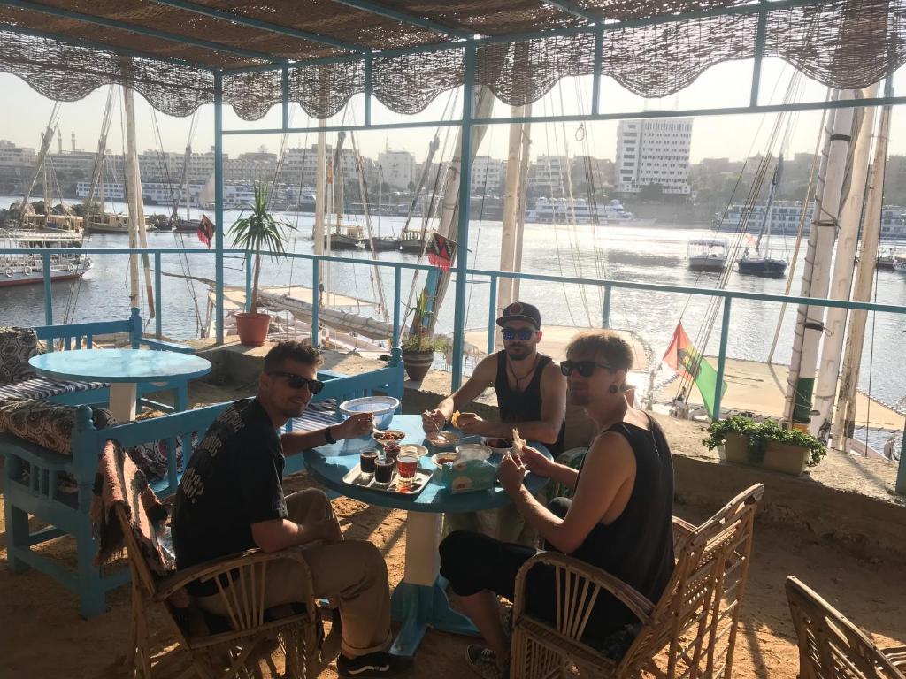 Eine Gruppe von Menschen, die an einem Tisch sitzen und Essen essen. in der Unterkunft Awi Guest House in Assuan