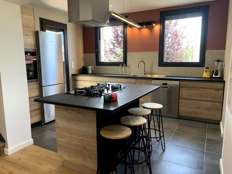 a kitchen with a black counter top and stools at Sol i Munt Cerdanya in Enveitg