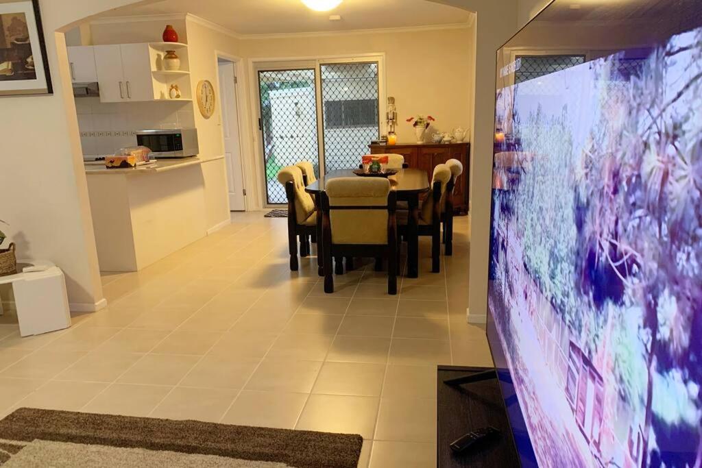 a dining room with a table and a large screen television at Sydney Blue Mountain Retreat in Kingswood