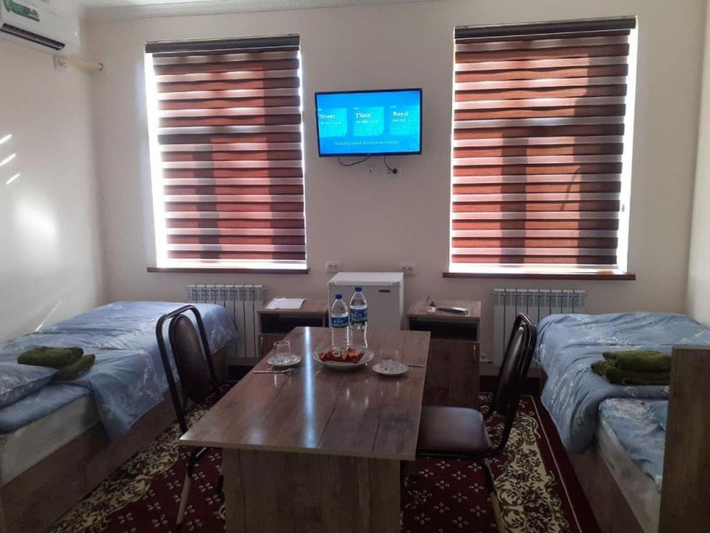 HOTEL ABU BAKIR في Denov: غرفة مع طاولة وسريرين وتلفزيون