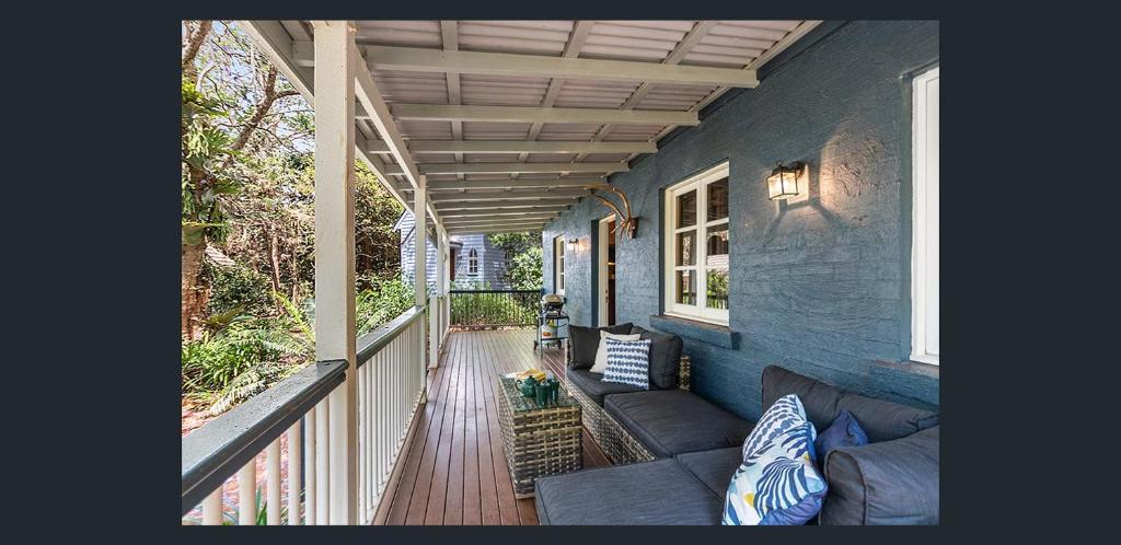 a porch of a blue house with a couch at The Gamekeepers Spa Cottage in Tamborine Mountain in Mount Tamborine