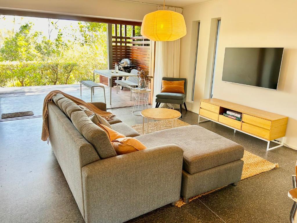 a living room with a couch and a television at Cosy Apartment at Sebel Twin Waters Resort w Private Garden - 2 Mins Walk to Beach & River in Mudjimba
