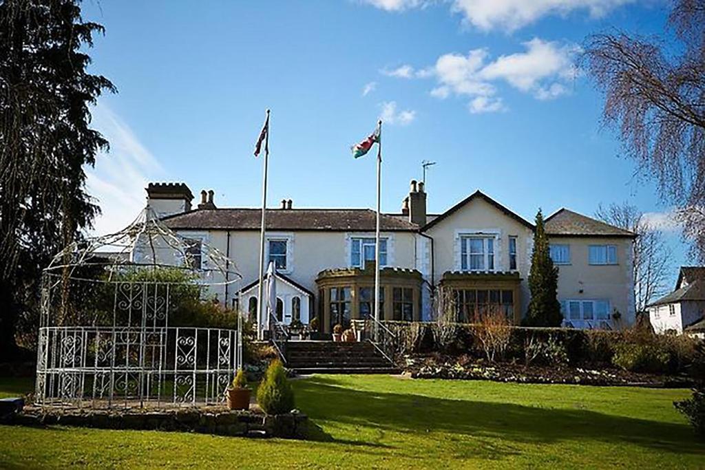 a large white house with two flags in the yard at Northop Hall Country House Hotel in Mold
