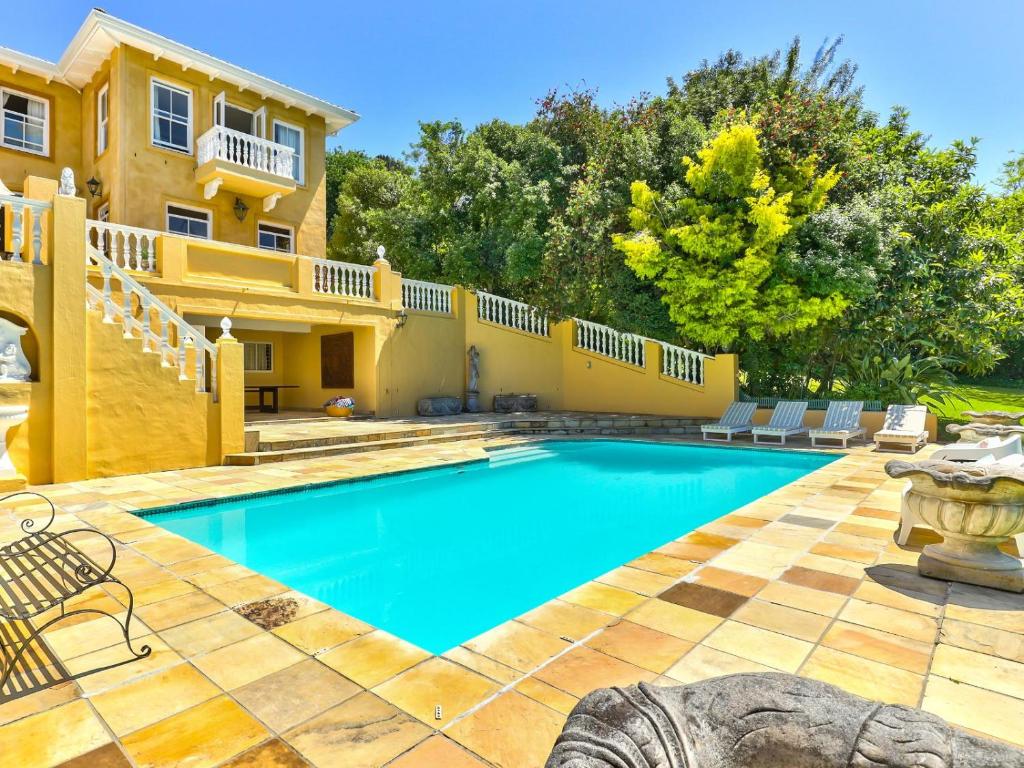 a villa with a swimming pool in front of a house at Devonport House - Constantia in Cape Town