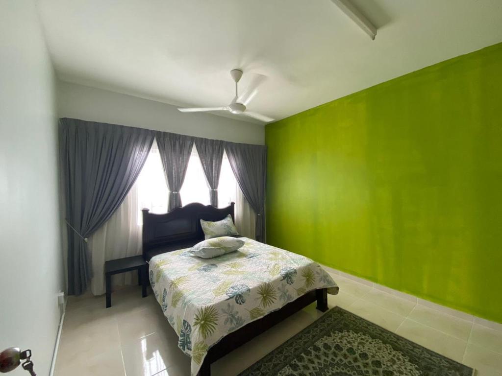 a green bedroom with a bed and a window at ALEENA STAYCATION @ APARTMENT TOK PELAM PANTAI BATU BURUK in Kuala Terengganu