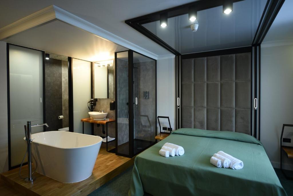 een slaapkamer met een bad, een bed, een bad en een wastafel bij Hotel Celis in Barcis