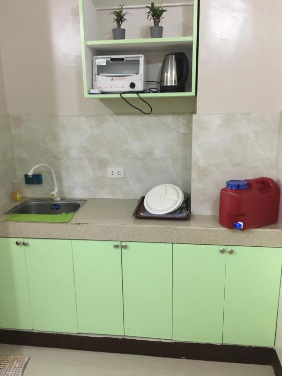 a kitchen with green cabinets and a sink and a microwave at AGB Anchorage Inn, studio room in Manila