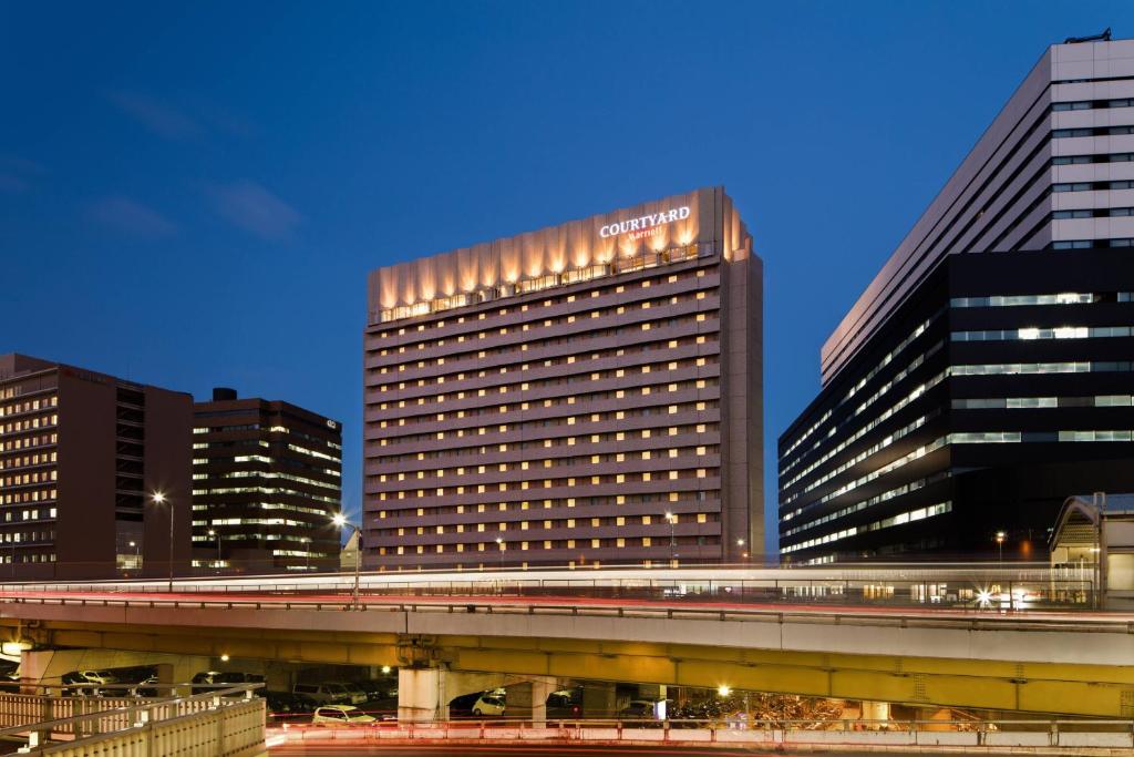 un edificio alto con un tren delante de él en Courtyard by Marriott Shin-Osaka Station, en Osaka