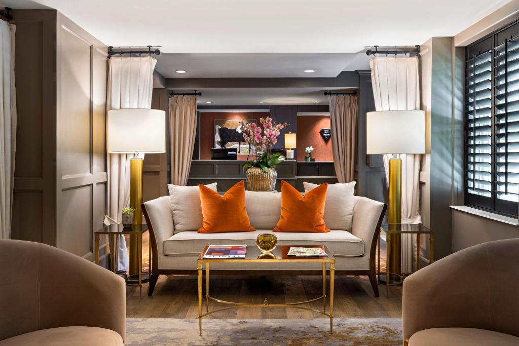 uma sala de estar com um sofá branco e almofadas laranja em Ambassador Hotel Oklahoma City, Autograph Collection em Oklahoma City
