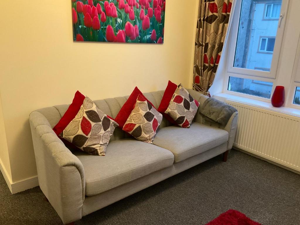 a couch with four pillows in a living room at 103 Nelson Street 1 st floor Right in Largs