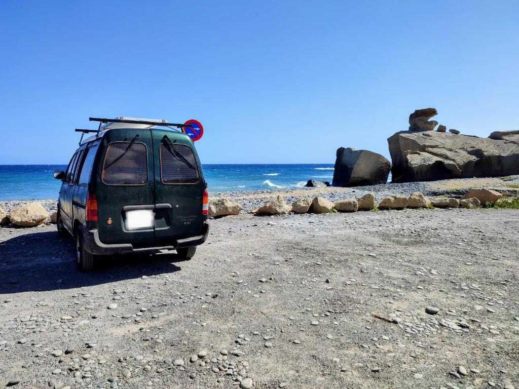 Beautiful Campervan to Rent في سانتا كروث دي تينيريفه: سيارة فان سوداء متوقفة على شاطئ قريب من المحيط