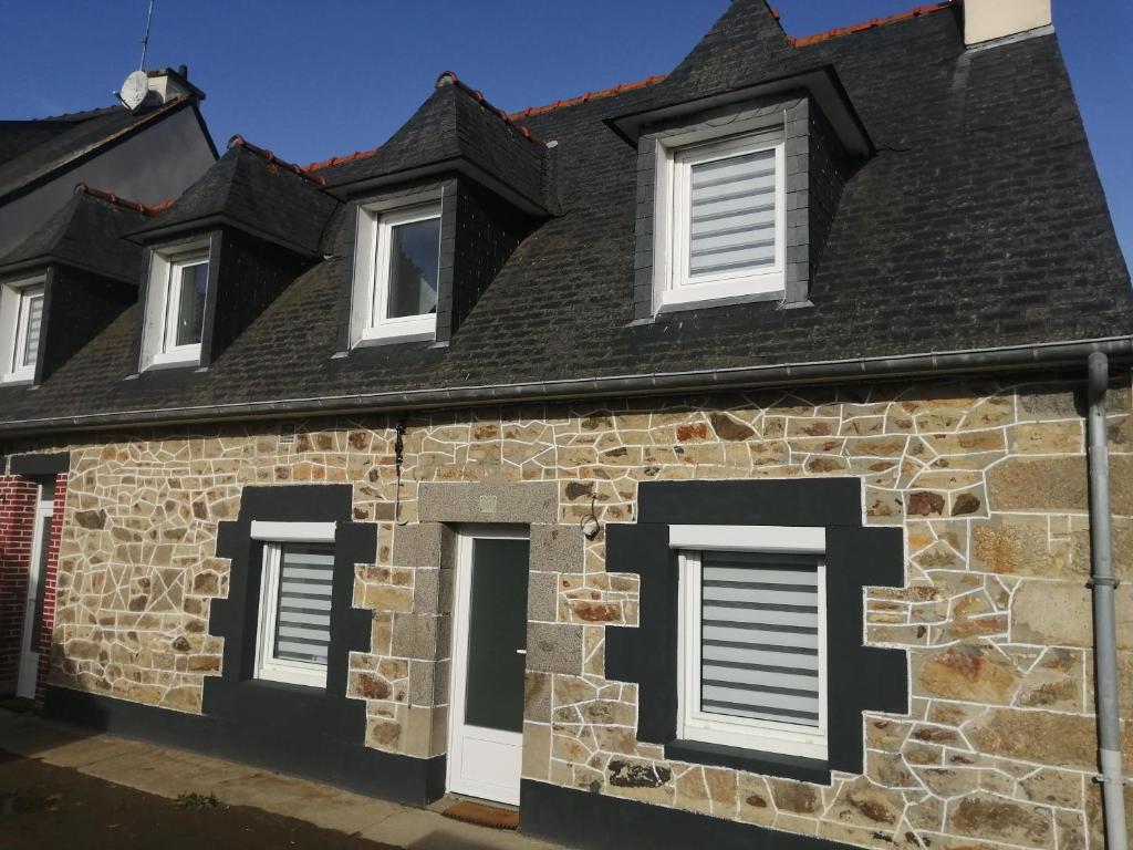 kamienny dom z czarnym dachem i białymi oknami w obiekcie Gite entre Paimpol et Erquy. Proche palais des congrès w mieście Ploufragan