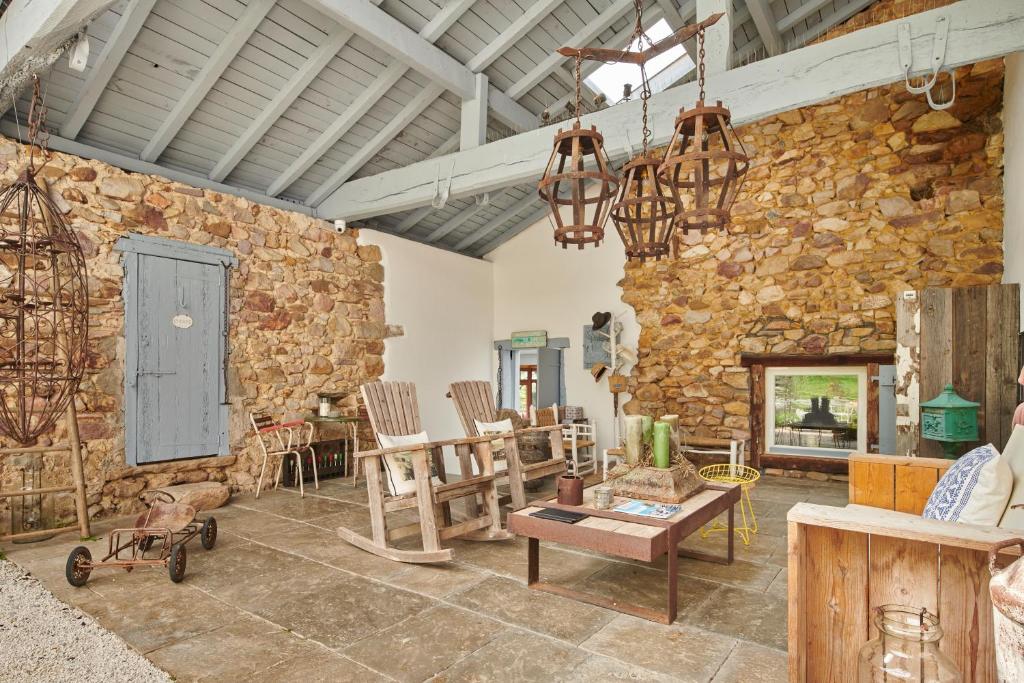 una sala de estar con una pared de piedra con mesa y sillas. en Ferme Elhorga, en Saint-Pée-sur-Nivelle