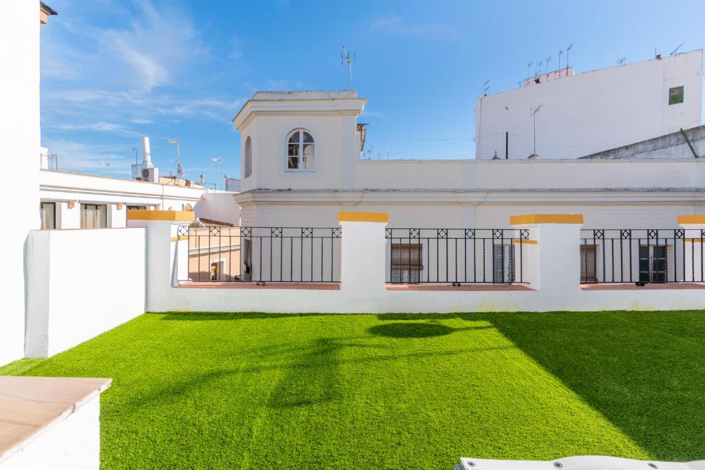 a white house with a green lawn in front of it at Santa Barbara Central Suites, Sevilla in Seville