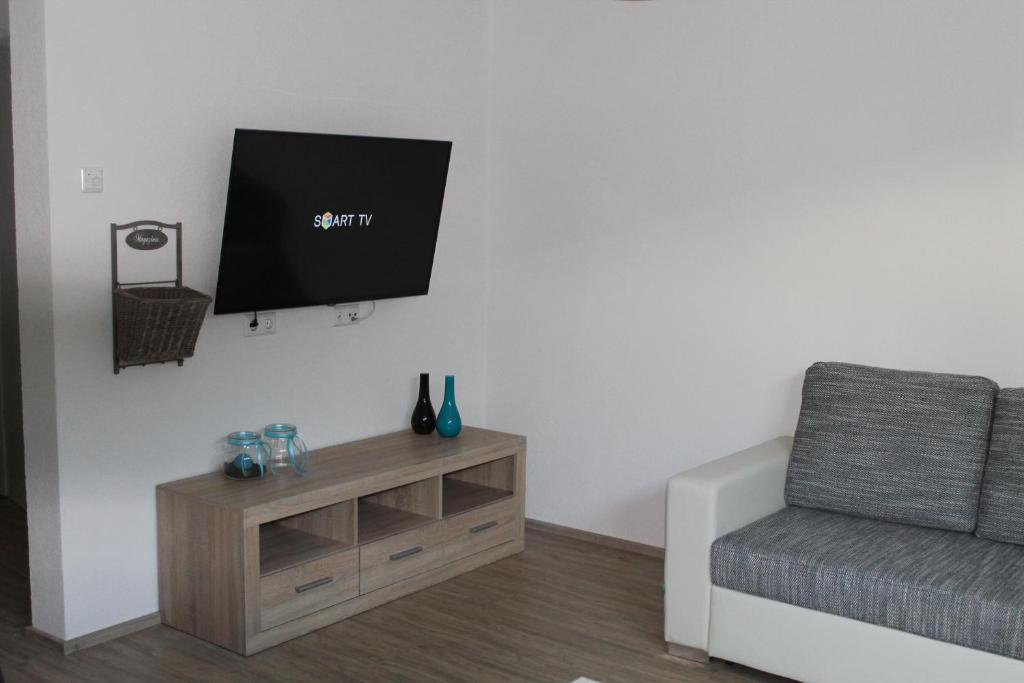 ein Wohnzimmer mit einem Sofa und einem TV an der Wand in der Unterkunft Ferienwohnung Pusteblume in Rheinhausen