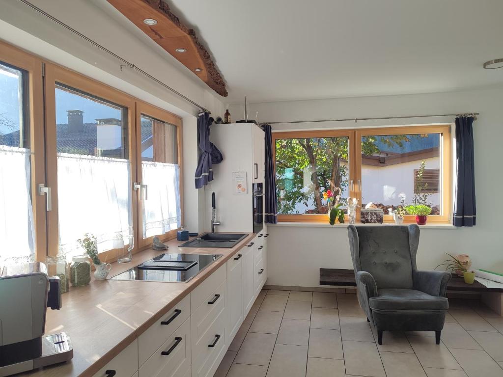 een keuken met een koelkast, een stoel en ramen bij Villa Mountainview in Bludenz