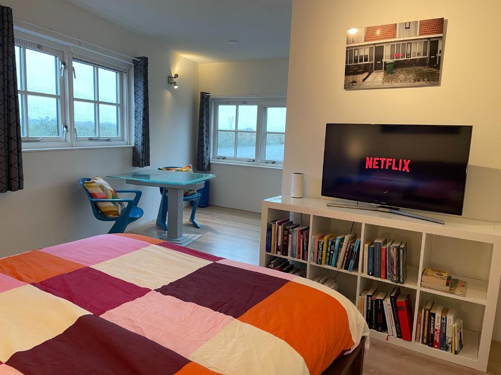 1 dormitorio con 1 cama, TV y mesa en Zelfstandig appartement - 10 minuten tot Amsterdam, en Ilpendam