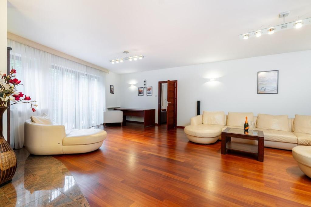 a living room with white furniture and a wooden floor at Royal Retreat Luxury Apartment Lazienki Park in Warsaw