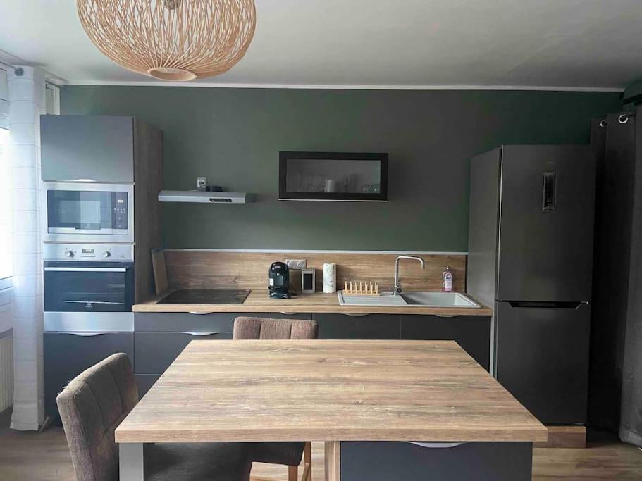 cocina con mesa de madera con sillas y fregadero en Studio de 28 m2 lumineux et élégant en Chambéry
