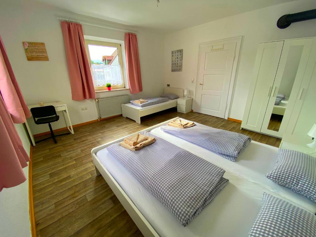 a bedroom with two beds and a table and a window at Ferienzimmer Fischach in Fischach