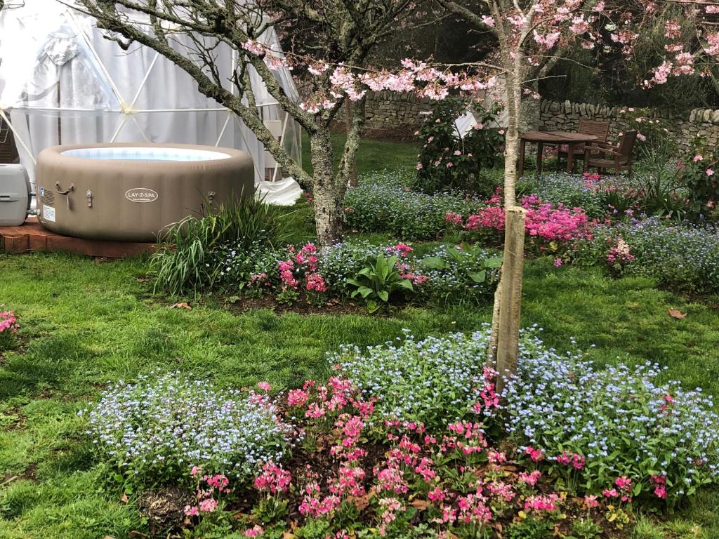 a garden with a bath tub in the middle of flowers at Flowerhaven - glamping dome in Hamilton