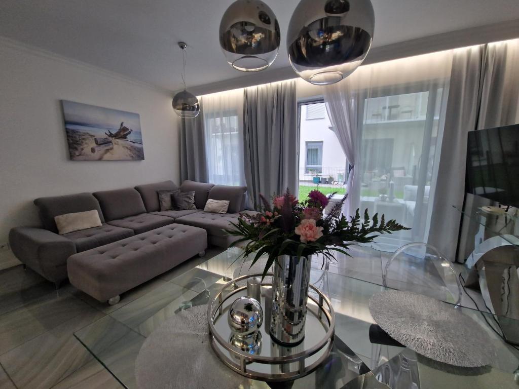 Maxim Apartment Pobierowo في بوبيروفو: غرفة معيشة مع أريكة وطاولة زجاجية
