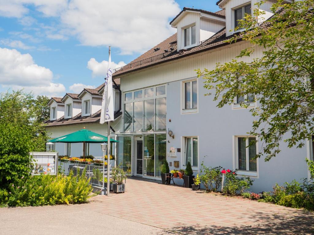 - un grand bâtiment blanc avec une terrasse en face dans l'établissement Altmühlberg Hotel & Restaurant, à Beilngries