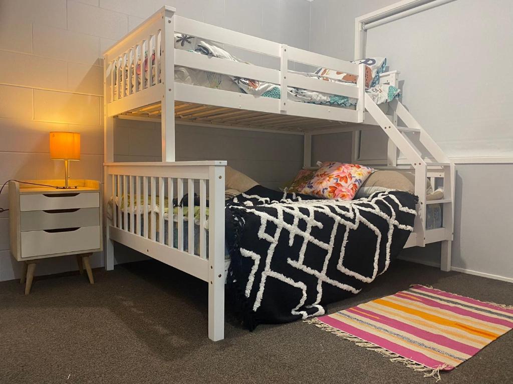 a bedroom with a white bunk bed and a ladder at Avondale Tidy Unit 1 in Auckland