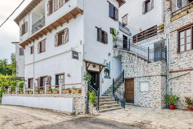 - un grand bâtiment blanc avec des escaliers et une porte dans l'établissement Makrinitsa Village, à Makrinitsa