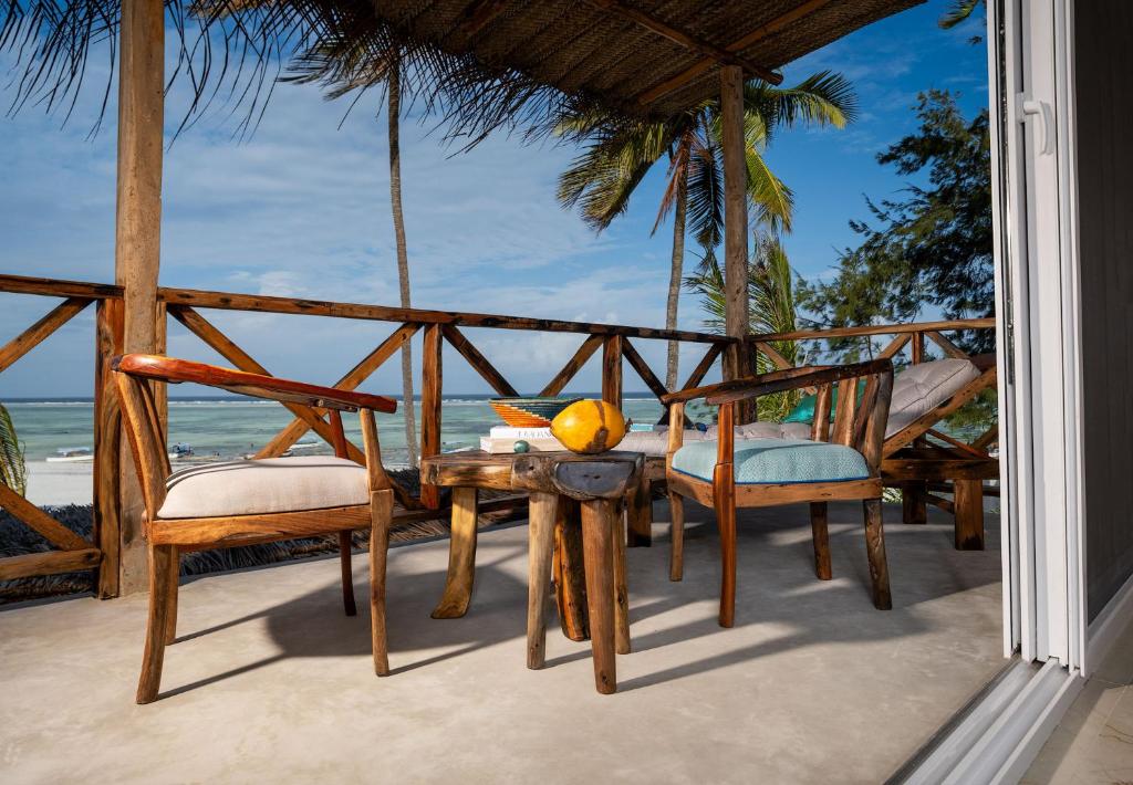 una mesa y sillas en un porche con vistas al océano en Infinity Beach Boutique Hotel & SPA en Matemwe