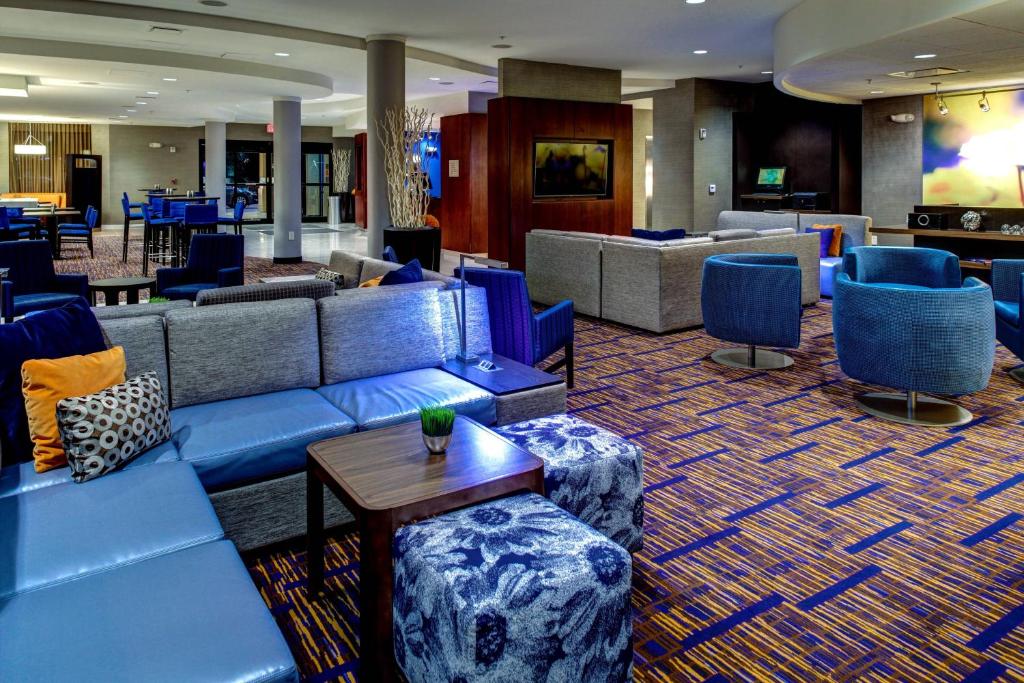 um átrio com sofás azuis, mesas e cadeiras em Courtyard Atlanta Airport West em Atlanta
