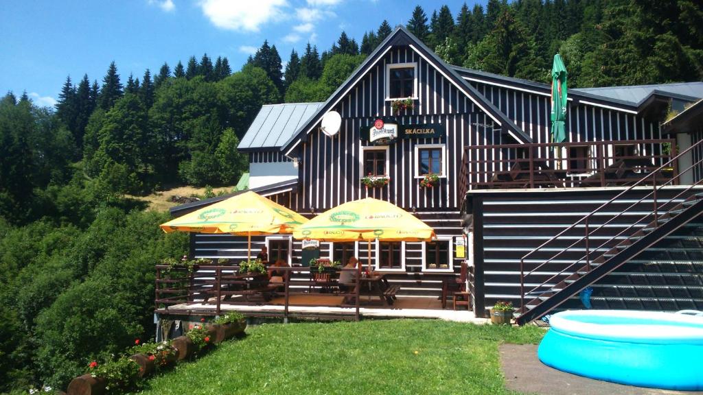 ein Haus mit Tischen und Sonnenschirmen davor in der Unterkunft Horská chata Skácelka in Rokytnice nad Jizerou