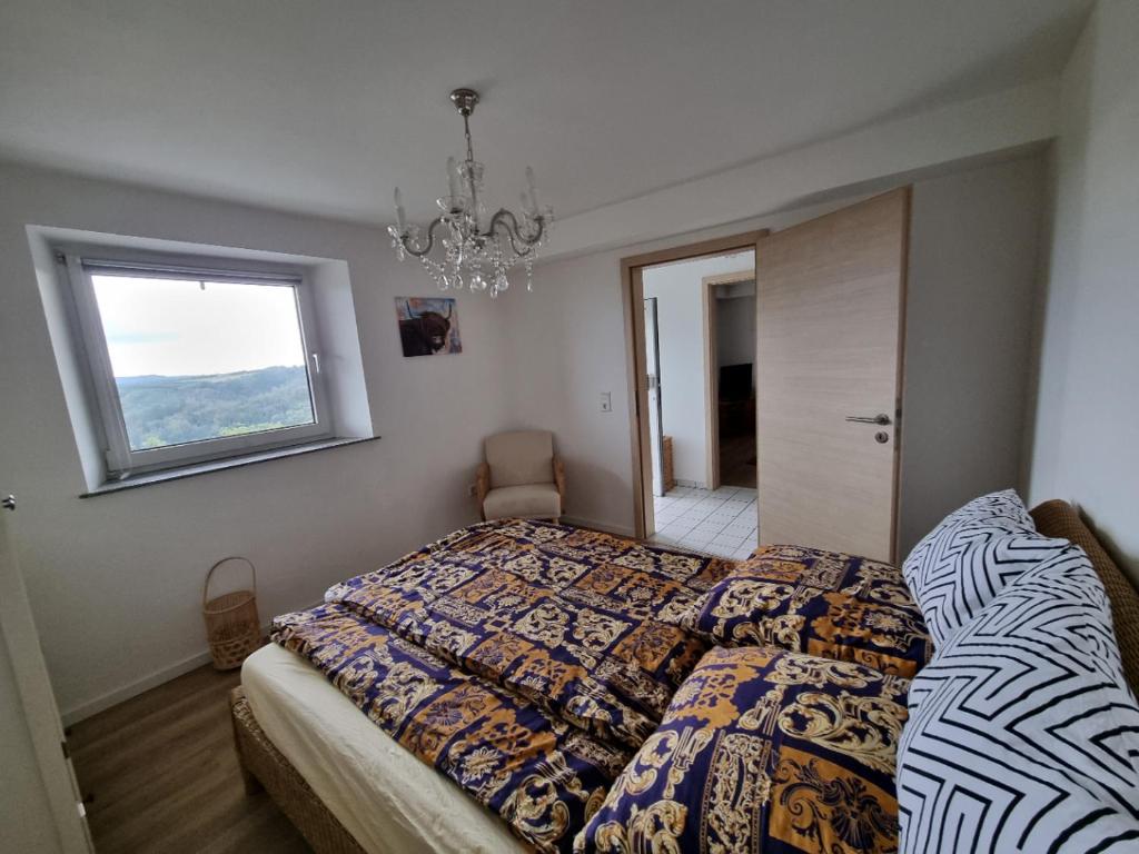 a bedroom with a bed and a window and a chandelier at Manderscheid Ferienwohnung mit Weitblick in Manderscheid