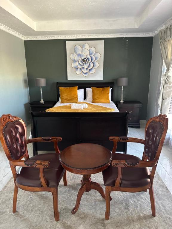 a bedroom with a bed with a table and two chairs at Kimberley Boutique Guest Lodge in Kimberley