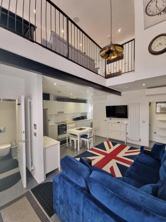 Deluxe Townhouse Zone 1 Brick Lane في لندن: غرفة معيشة مع أريكة زرقاء ومطبخ