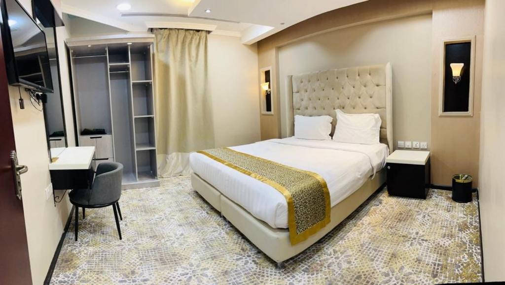 a bedroom with a large white bed and a desk and a chair at اصالة الشروق للشقق المخدومه in Al Khobar