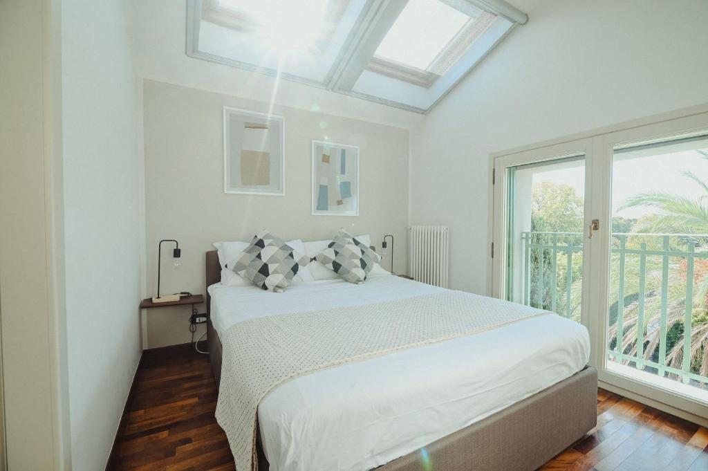 a white bedroom with a bed and a window at Angolo a Corte in Pietrasanta